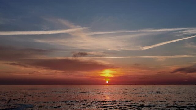 A cinematic time-lapse sequence capturing a vibrant, golden-hour sunset over the Atlantic Ocean at Furadouro Beach in Ovar, Portugal. The footage features the sun slowly descending toward the horizon,