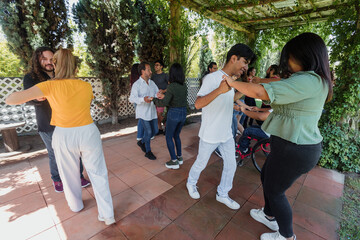 Fototapeta premium Group of latino friends in a salsa dancing class outdoors in Mexico Latin America. Hispanic people moving to the rhythm and having a fun together
