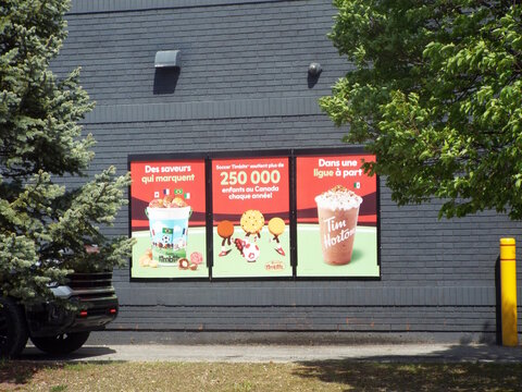 Gatineau,Quebec, Canada &ndash; May 21, 2026:A brick wall displays three promotional "Tim Hortons posters" in French, highlighting "soccer Timbits for Canadian children annually" on Chem. de la Savane.