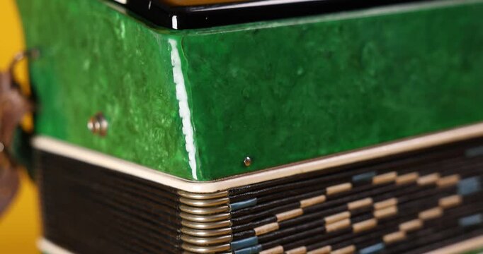 Piano accordion on yellow background, closeup. Camera moving up