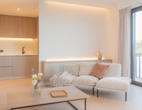 A close-up of a very modern living room featuring simple, concealed modern lighting and floral accents; the new furniture avoids a futuristic look, complementing the open-plan layout shared with the k