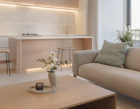 A close-up of a very modern living room featuring simple, concealed modern lighting and floral accents; the new furniture avoids a futuristic look, complementing the open-plan layout shared with the k