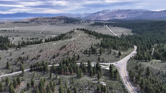 Aerial view of a mountain highway winding through pine forests and rolling hills in California