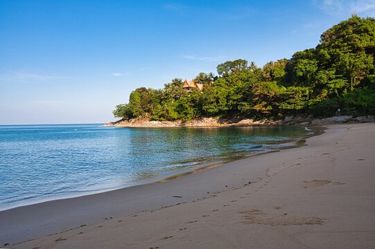 Tropical beach cove with lush green headland and villa rooftops, Banana Beach, Phuket, Thailand