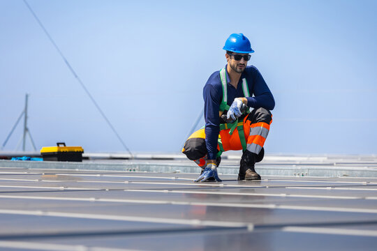 Solar panel technician checking maintenance on rooftop, Renewable energy worker inspecting solar panels in a solar power plant, Electrical engineer in safety gear working with solar energy system