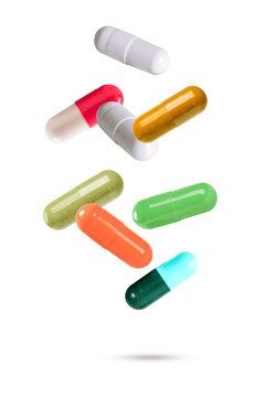 Colorful medical capsules and herbal supplement pills falling in the air. Healthcare and pharmacy concept isolated on white background.