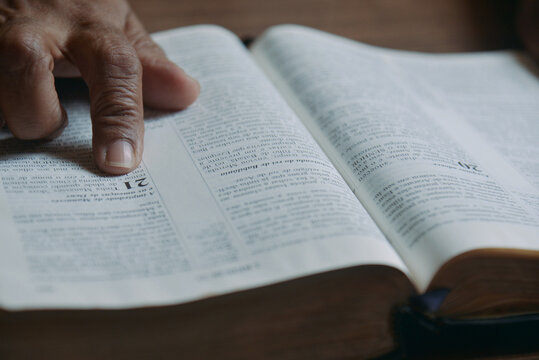 Person reading the Holy Bible with their finger pointing to the biblical passage. Concept of religiosity and reflection.