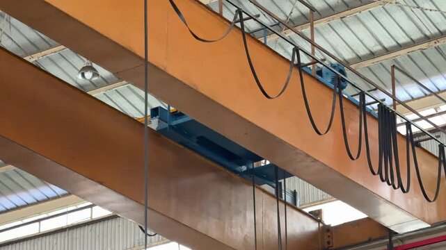 an overhead bridge crane in a manufacturing plant. Heavy lifting machinery designed for industrial transport and workflow efficiency.