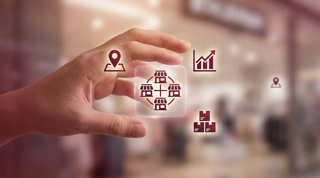 Hand holding virtual franchise network icons with store location growth graph and inventory management system in retail store mall background concept