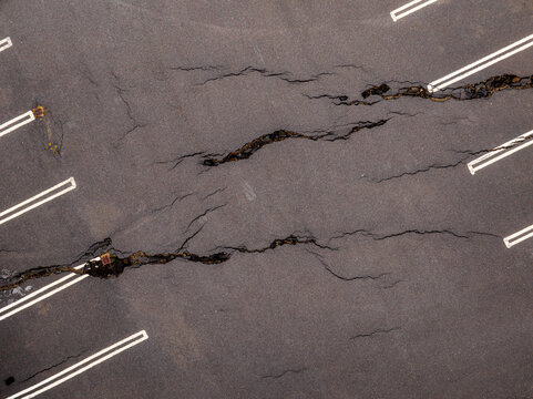 Aerial view of deep fissures and cracks in the asphalt surface of a parking lot in Iceland.