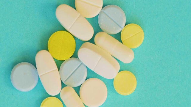 Colorful pills scattered on a bright blue surface. Medical themes, health, or wellness concepts. Ideal for pharmaceutical or health-related visuals