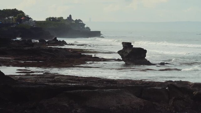 Coastal Tanah Lot Temple Silhouette At Sunrise, Misty Cliffs And Gentle Surf, Distant Pagoda On Rocky Promontory, Serene Pilgrimage Mood, Drone Travel Sweep, Soft Teal Tones And Slow Reveal,Bali.