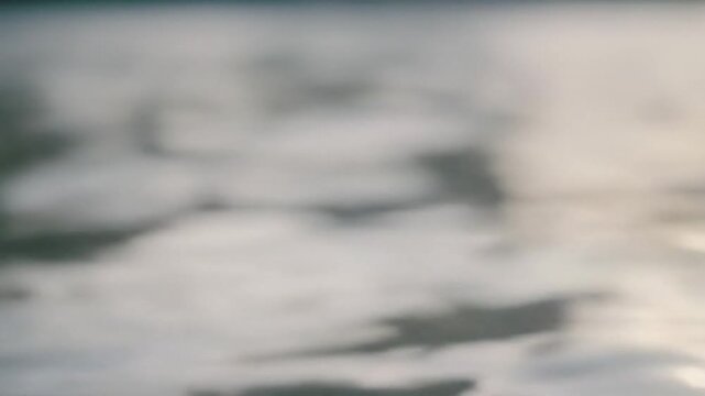 Abstract blurred water surface background with soft light bokeh and peaceful ripple reflections on calm ocean or lake template