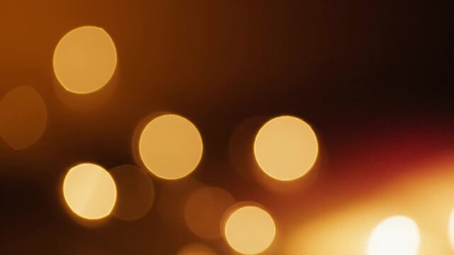Abstract golden bokeh background with warm glowing out of focus light circles on dark backdrop for festive holiday design concept