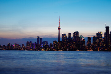 Obraz premium Toronto skyline at dusk with illuminated city lights reflecting on the water, vibrant urban night view. g.