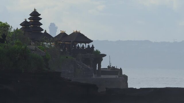 Calm Sunrise Over Tranquil Tanah Lot Temple Setting. Early Morning Mist Surrounds Silhouetted Temple On Cliff Edge. Gentle Waves And Golden Light Create Peaceful Atmosphere, Bali, Indonesia