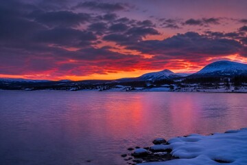 Fototapeta premium Nordic winter lake at dusk with a purple-red sunset sky.