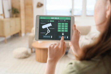Person controlling smart home security system on tablet © Pixel-Shot