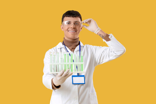 Male chemist with test tubes on yellow background