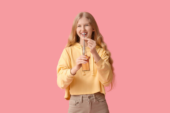 Beautiful young woman with bottle of soda on pink background