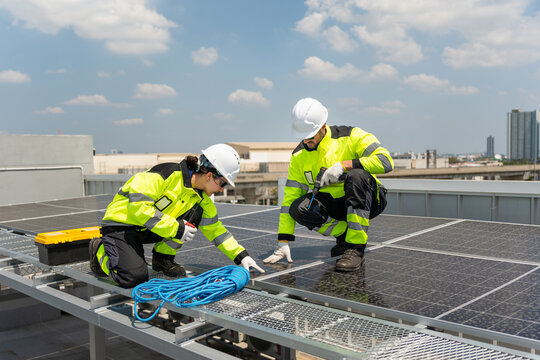 Technicians installing solar panels on rooftop, Solar energy engineers working on rooftop solar power plant installation, Renewable energy concept with workers maintaining solar photovoltaic panels