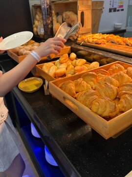 Person Selecting Fresh Pastries at Hotel Breakfast Buffet