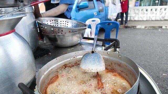 Street Vendor Frying Chicken in Hot Oil at Bangkok Market