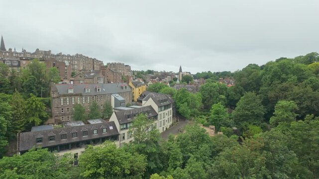 Scenic view of historic stone buildings and lush trees in Dean Village, Edinburgh.