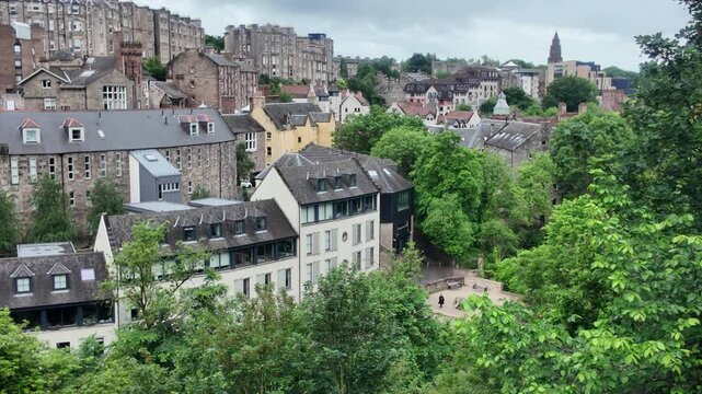 Well Court red sandstone buildings along the Water of Leith in Dean Village, Edinburgh. Historic architecture with lush riverside greenery.