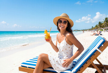 Obraz premium Smiling woman in straw hat and sunglasses with cocktail on beach chair