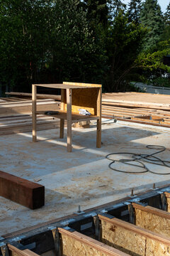 Temporary work table built and standing on poured concrete foundation surrounded by i-beam floor joists, new house build construction project
