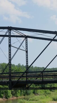 Scenic view of a historic country mill site featuring an old iron and wooden bridge, rustic log cabin, and flowing river on a summer day