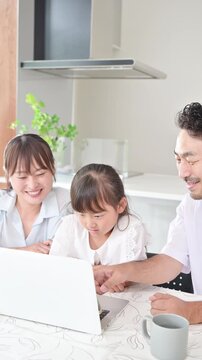 ノートパソコンを見る情報収集をする親子3人の家族(ファミリー)　家族旅行や受験の習い事や塾を探す子育ての教育などのライフスタイルイメージの縦動画　一緒に笑顔で指を差す
