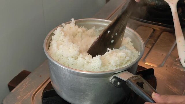 Close-up video of freshly cooked white rice in a metal pot on a gas stove, representing traditional home cooking and staple food preparation in Southeast Asia.
