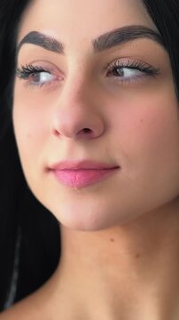 Vertical video. Face beauty. Healthy hair. Tender young woman with long dark locks blowing on wind. Female facial glamour cosmetics.