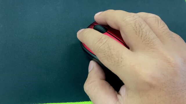 man hand using a red wireless computer mouse on a black mousepad