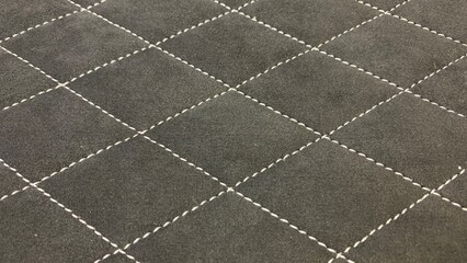 Fototapeta premium Black quilted fabric surface featuring diamond stitching pattern, suitable for upholstery, automotive, and decorative applications