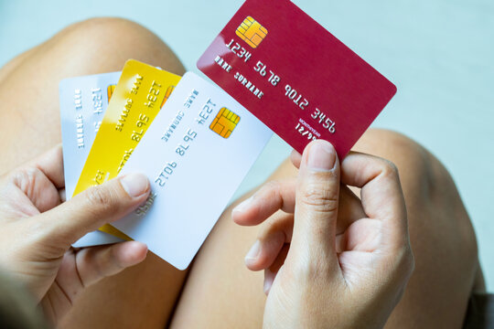 Close up of hand human holding multiple color credit cards, choosing a red card for payment, concept of consumerism, financial management, debt and cashless society and saving money	