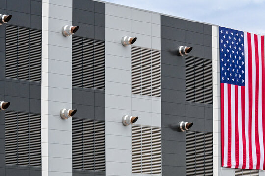 Exterior of a hyperscale data center featuring ventilation exhaust systems and a large American flag, representing secure digital infrastructure, cloud computing, and technology operations