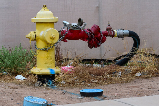 Yellow fire hydrant connected to a red backflow prevention assembly beside a commercial property, illustrating fire protection, water infrastructure, and utility systems
