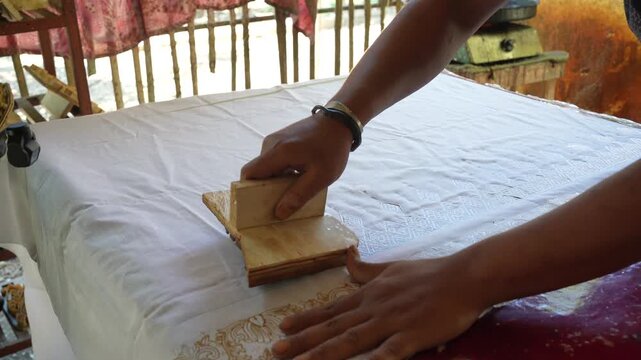 Hand Pressing Wooden Batik Block on Fabric in Indonesian Workshop