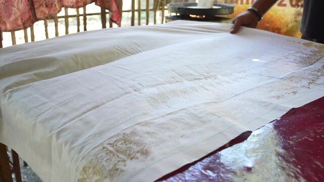 Hand Pressing Wooden Batik Block on Fabric in Indonesian Workshop
