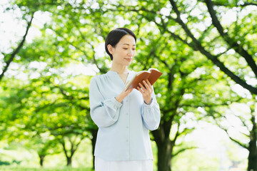 Fototapeta premium 屋外で読書をする若い女性 ライフスタイルイメージ