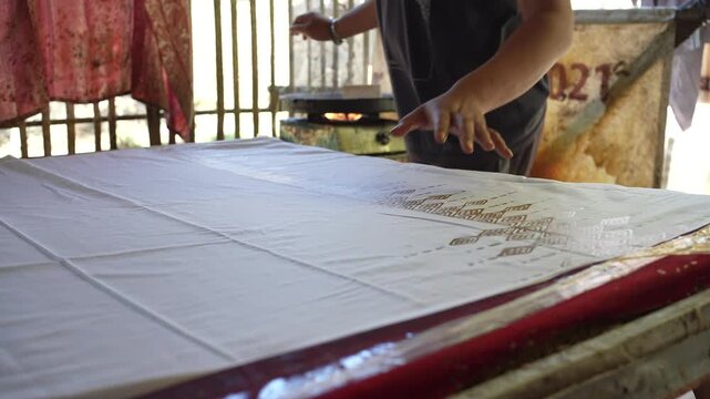 Indonesian Artisan Stamping Batik Fabric with Traditional Wooden Tool