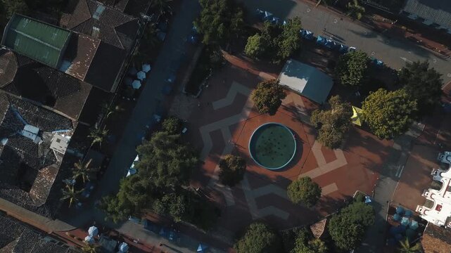Aerial drone view over quaint town square with central fountain in colonial village.