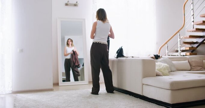 Daily routine. Stylish woman. Professional entrepreneur wearing blazer preparing for workday at cozy home using mirror interior.