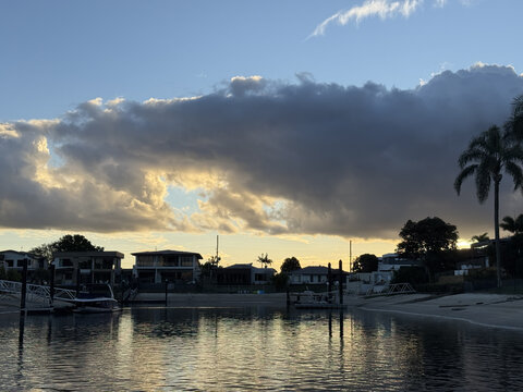 Waterfront Luxury Homes Along Canal at Sunset with Dramatic Clouds