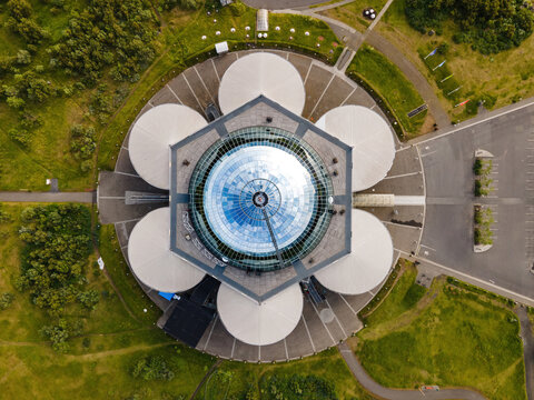 Aerial view of Perlan, a landmark building with a glass dome and six large water tanks, surrounded by green parkland in Reykjavik, Reykjavikurborg, Iceland.