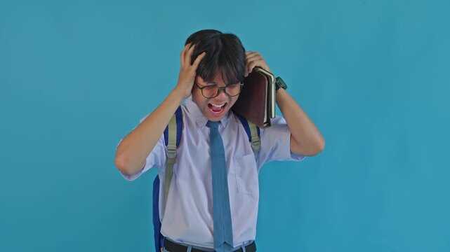 Frustrated Asian male student pulling hair and feeling overwhelmed 