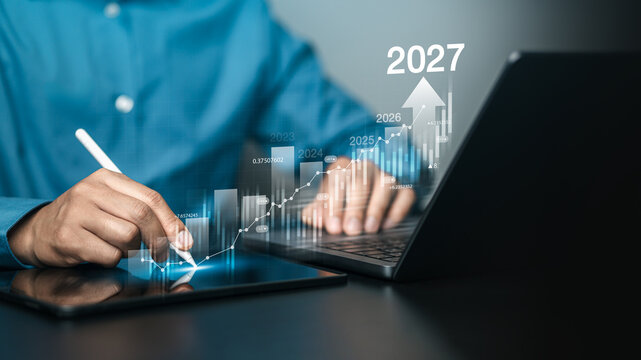 Businessman analyzing financial growth chart for 2027 Stock market finance and profit growth concept with increasing financial trend on revenue graph.